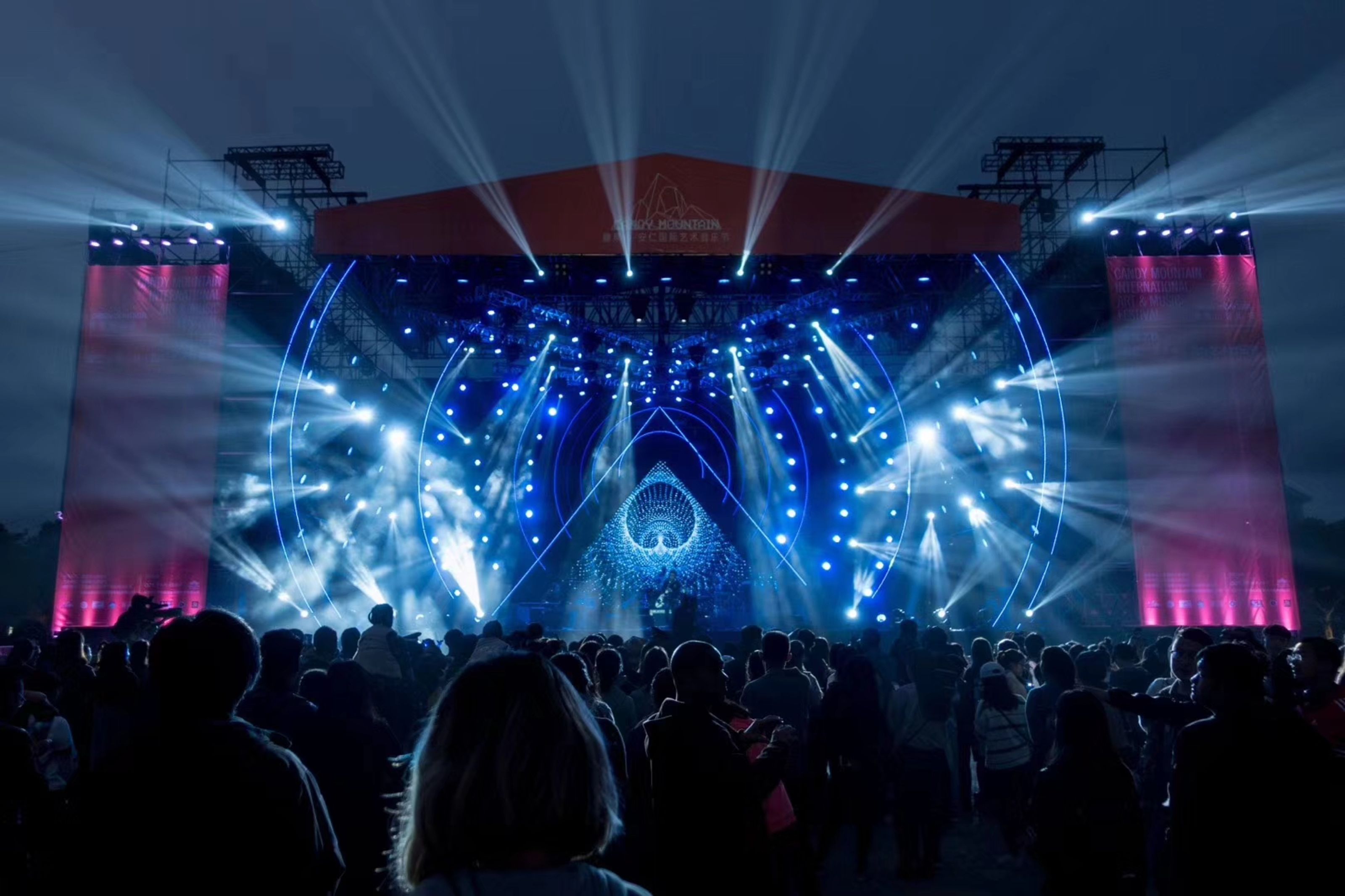Festival main stage lit in blue with a large crowd